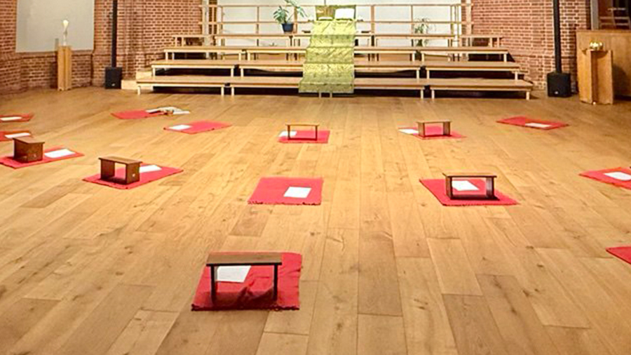 Mehrere Gebetsbänkchen auf roten Decken sind zum Altar ausgerichtet.