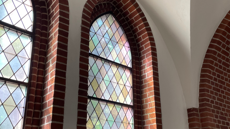 Sonne scheint durch Buntglasfenster in die Kapelle