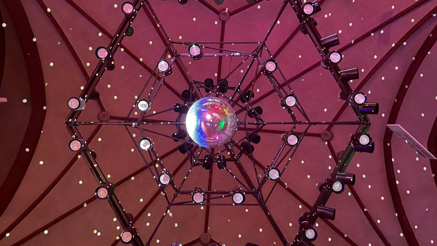 Blick nach oben auf Discokugel und 6-eckige Lampenkonstruktion an der Kirchendecke