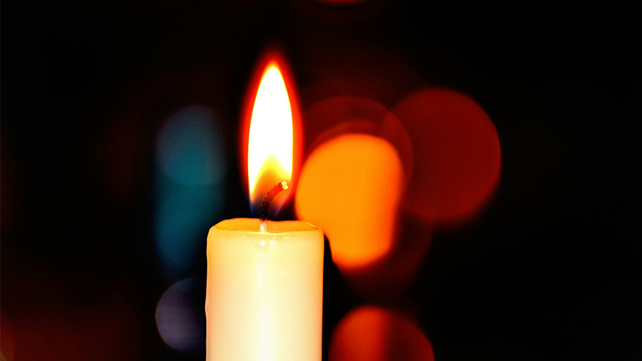 Brennende Kerze und orangefarbene Lichtreflexe