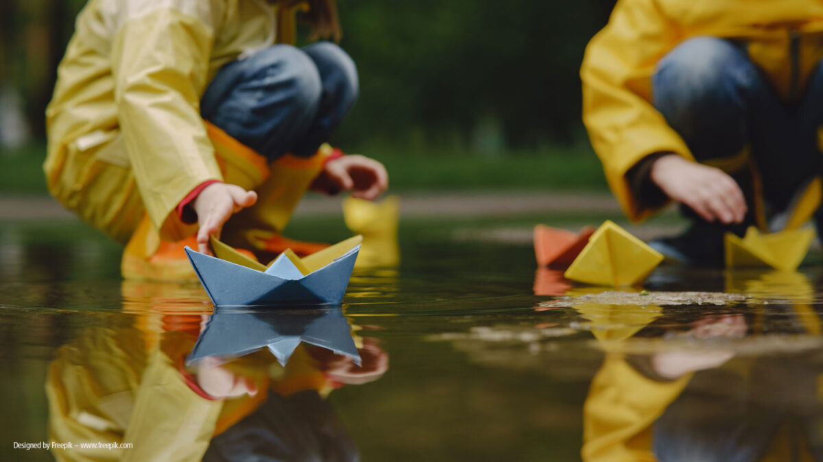 Kinder spielen mit Papierbooten in Pfütze