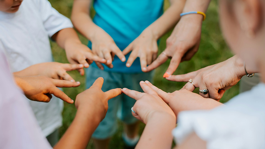 Kinder halten ihre Finger so in die Mitte, dass ein Kreis entsteht.