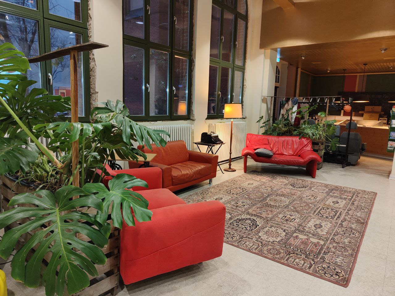 Sitzecke mit roten Sofas, Stehlampe und Grünpflanzen